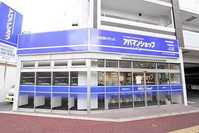角地に立つ店舗の外観。二面のガラス面と大きな看板で遠距離からも視認できるつくり